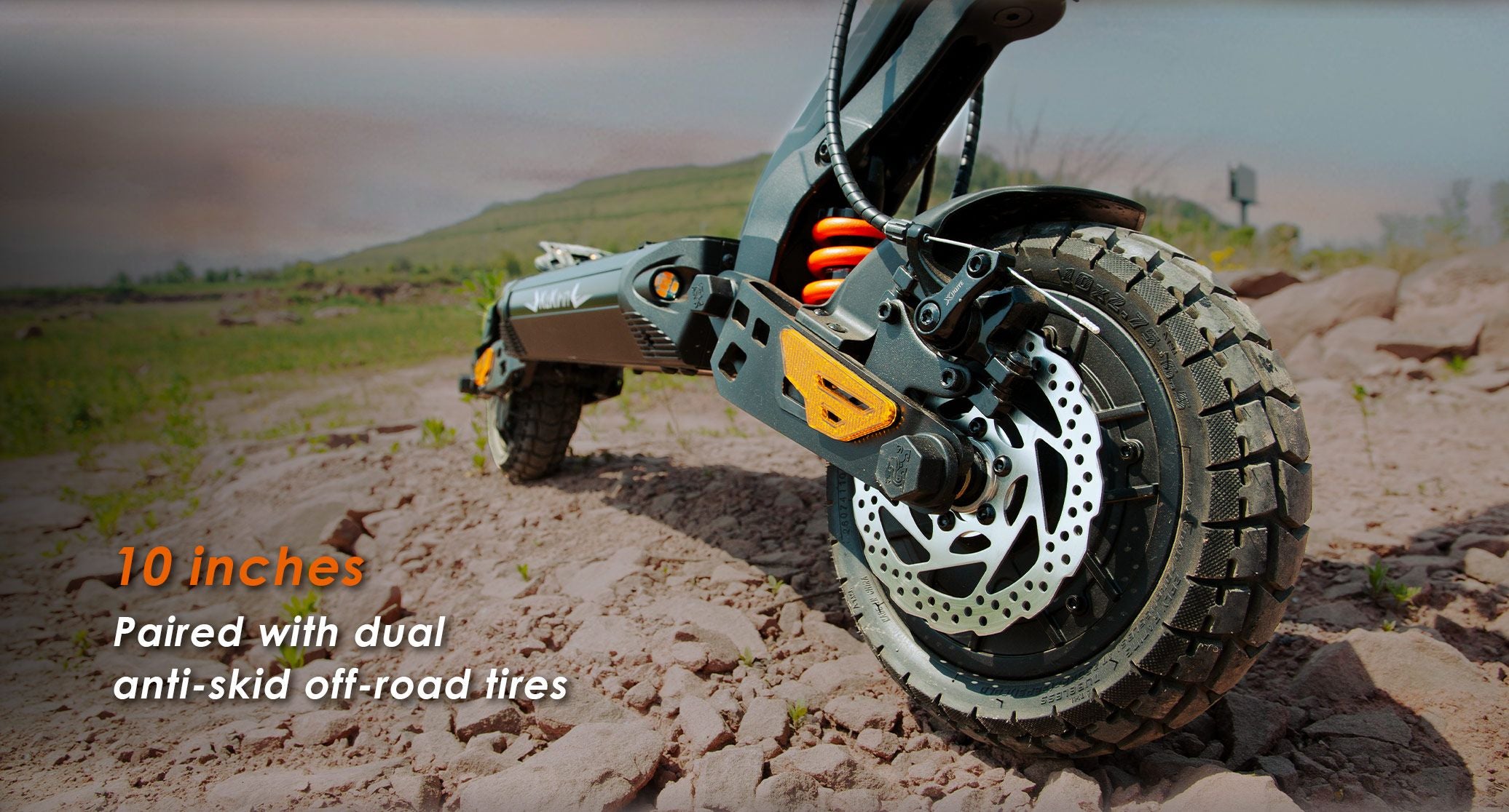 KuKirin G2 Master close‑up of 10‑inch anti‑skid off‑road tire, disc brake and dual suspension on rocky terrain