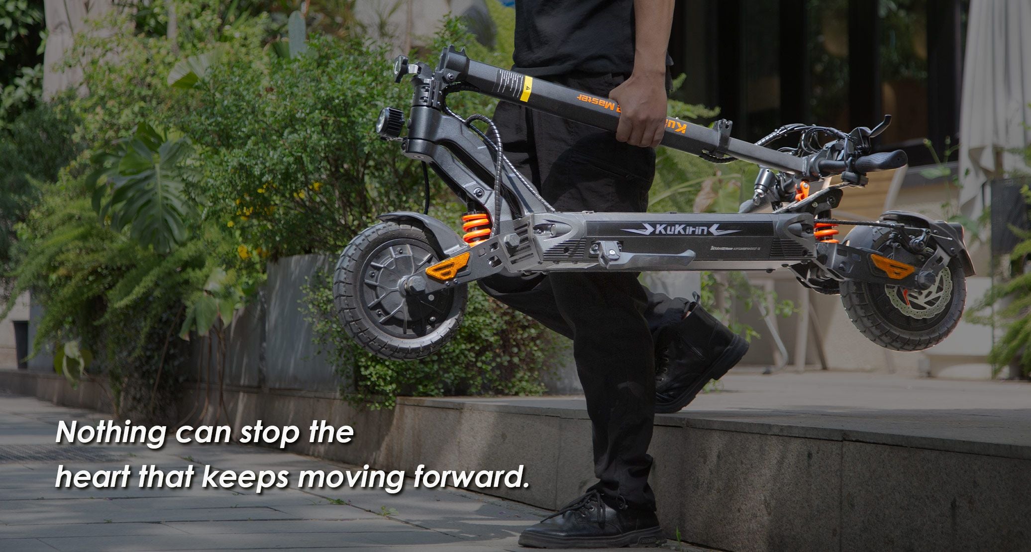 Person carrying folded KuKirin G2 Master electric scooter, showing portability for climbing stairs