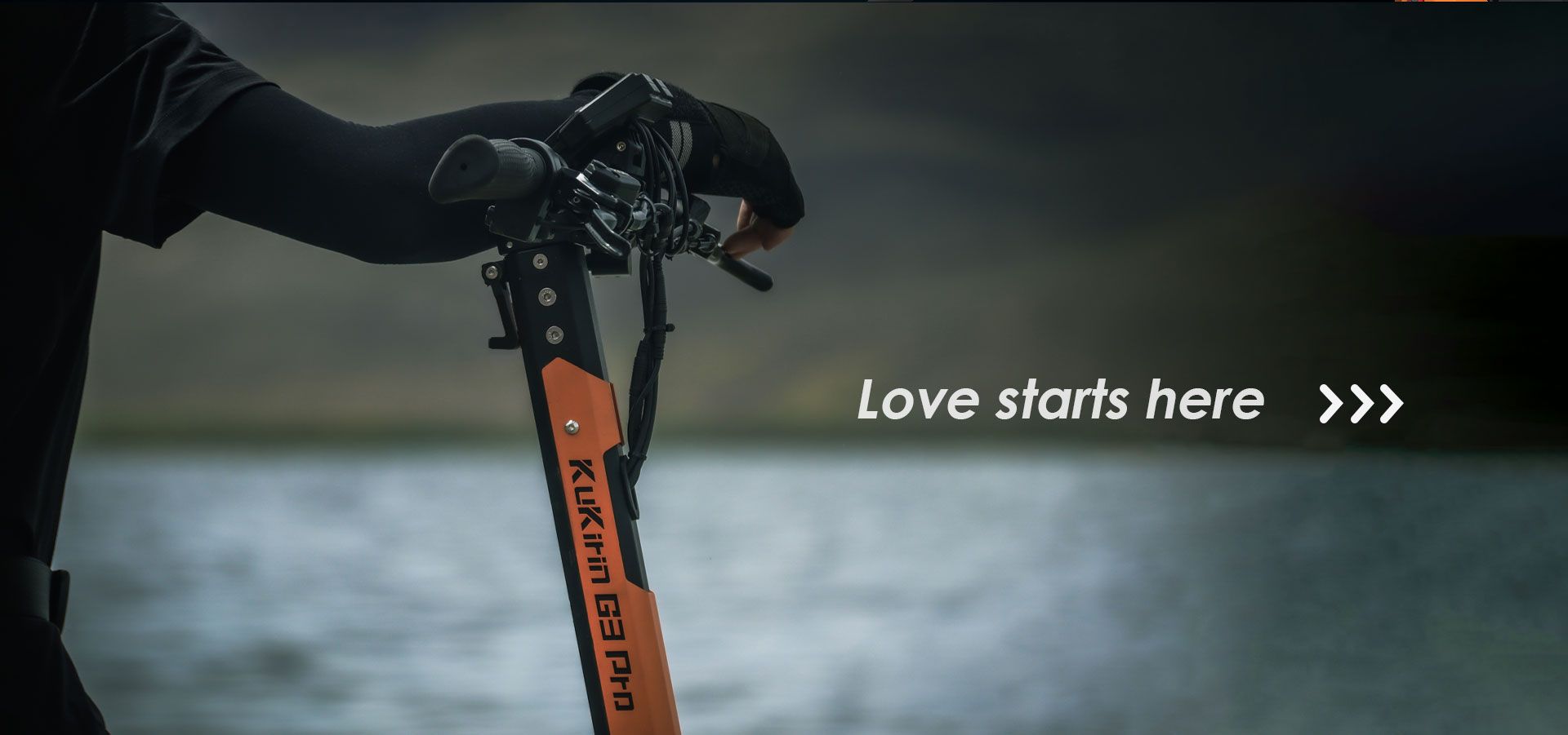 KuKirin G3 Pro electric scooter handlebar close‑up outdoor lakeside lifestyle shot with rider hand gripping controls
