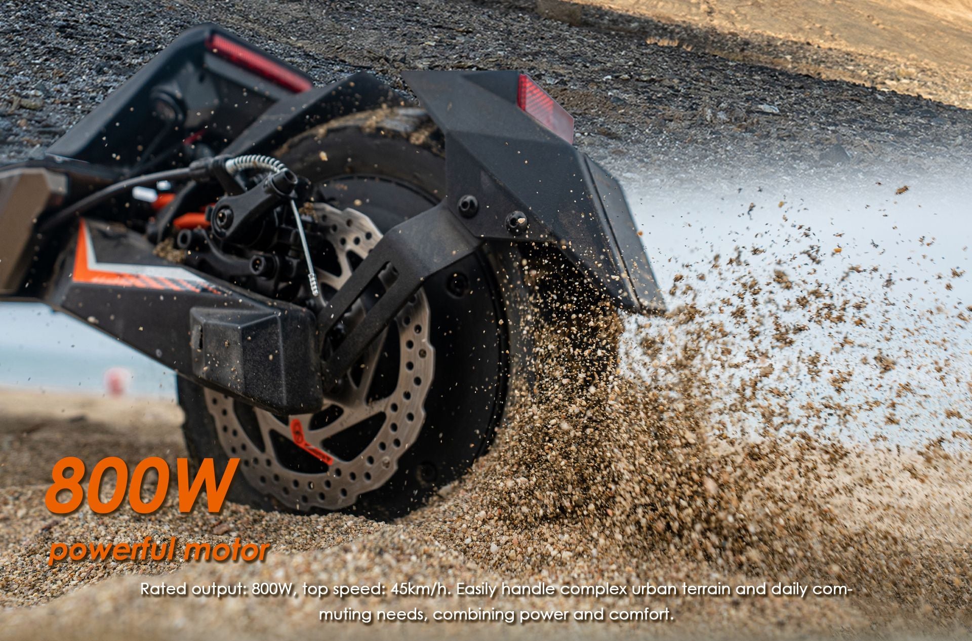 KuKirin T3 electric scooter rear 800W hub motor and disc‑brake close‑up, kicking up sand on off‑road terrain
